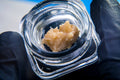 Close-up of a clear glass jar with cambodian haze rosin.