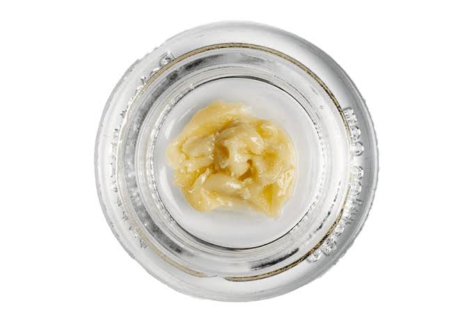 Close-up of a clear glass jar with grape grenade rosin.
