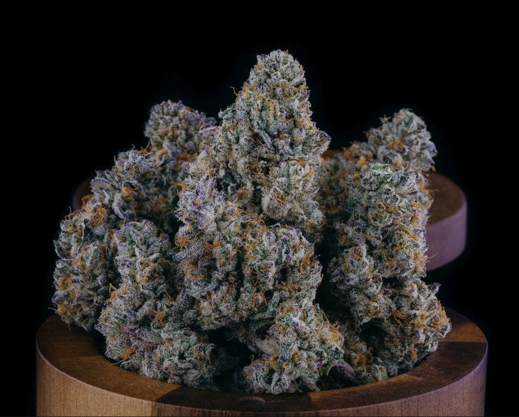 Large cannabis bud on a wooden stand against a black background
