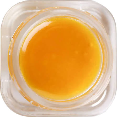 Close-up of a clear glass jar with neon runtz live resin.